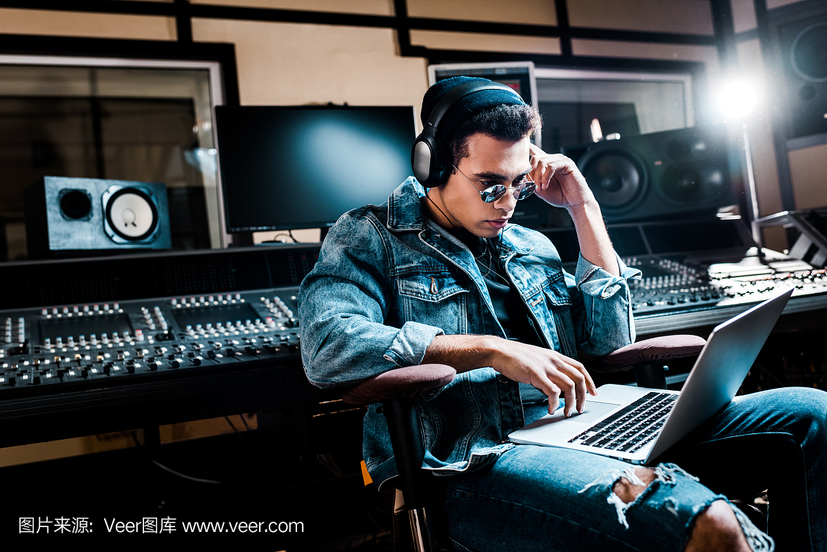 集中混合種族聲音制作人耳機使用筆記本電腦在錄音室